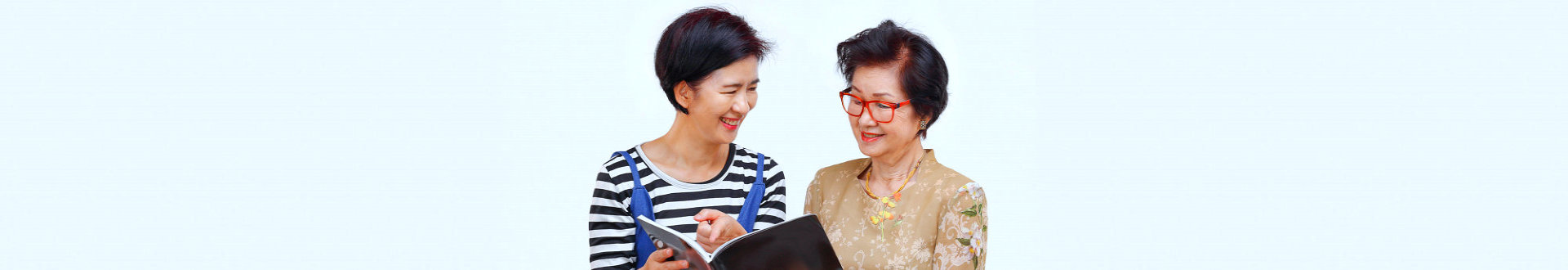 caregiver and a senior woman reading a magazine